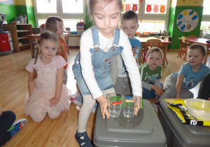 Dziewczynka umieszcza szkło na pojemniku na szklane odpady